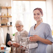 Standing near pensioner. Smiling medical attendant standing near pensioner wearing glasses